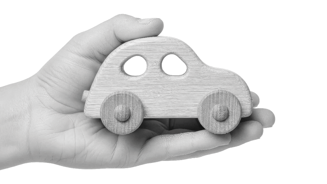 A gentle hand cradles a smooth, light-colored wooden toy car, showcasing its rounded shape and simple design against a stark black background, evoking a sense of childhood innocence and simplicity.